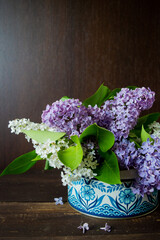 white and purple liliac in a blue pattern box with dark brown wooden wall