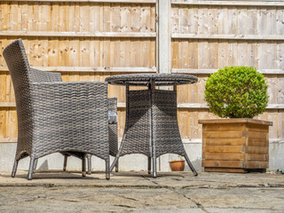 Grey Rattan garden chairs and table laid out on a patio