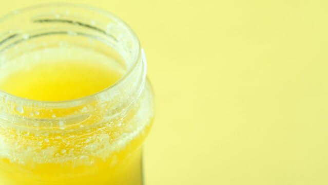 close pu of homemade ghee in container on yellow background 