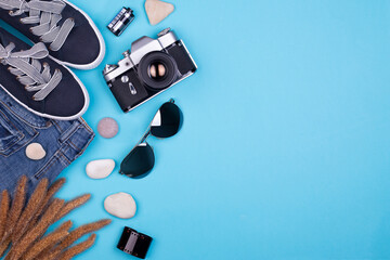 Traveler accessories on blue background with camera and sunglasses. Concept of summer travel or vacation. Flat lay, top view.