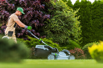 Garden Worker with Grass Mower Working in Residential Garden - obrazy, fototapety, plakaty