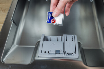 girl loads a tablet into the dishwasher. girl washes dishes in the dishwasher.