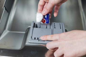 girl loads a tablet into the dishwasher. girl washes dishes in the dishwasher.