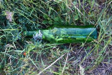 A bottle thrown into nature as garbage. A glass bottle that pollutes the environment. Environmental pollution.