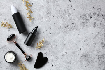 Set of luxury skin care cosmetics. Flat lay black face roller, jar or moisturizer cream, gua sha, essential oil, serum on stone table. © photoguns