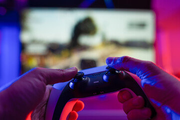 Close-up. Gamepad in the hands of a gamer on a technological background. Neon lighting. Video games on modern equipment, new digital technologies, cyberspace, cybersport.