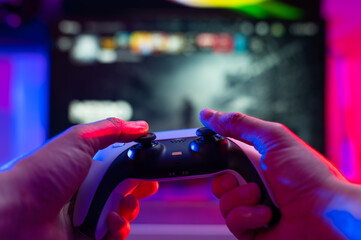 Close-up. The gamer holds a joystick in his hands. Plays video games on modern digital gaming equipment. Cyberspace, cybersport, game strategy, passion, excitement.