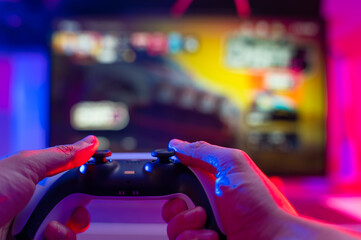 Joystick in hand. A gamer plays video games on a technological background. Neon lighting. Cybersport, cyberspace, communications, virtual reality.