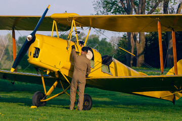 The yellow historic plane is being prepared for flight.