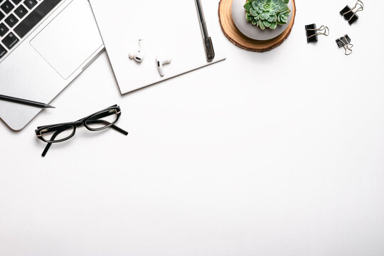 Top view above of white office desk table with keyboard, notebook and pen, glasses, headphones, succulent and other office supplies. Workplace, Flat lay, copy space. Concept business and finance.