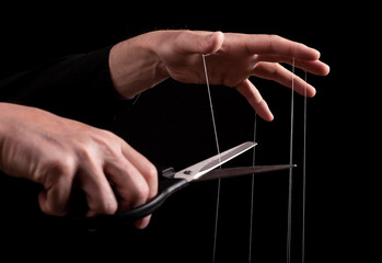 Overcoming addiction. Man cutting strings on fingers with scissors. Freedom, liberation from...