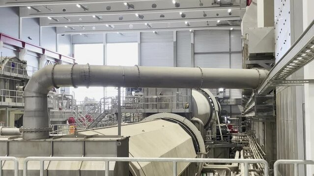 Eine sich in Betrieb befindliche riesige Papiem&uuml;hle in einer Fabrikhalle.