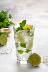 One glass with cold mojito with ice, lime and mint. Fresh Lemonade, tonic on grey background