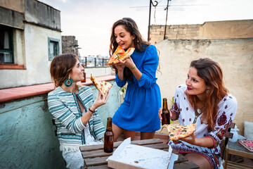 Happy women enjoying dinner party on a rooftop in Barcelona