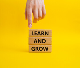 Learn and grow symbol. Concept words 'Learn and grow' on wooden blocks. Beautiful yellow background. Businessman hand. Business and Learn and grow concept. Copy space.