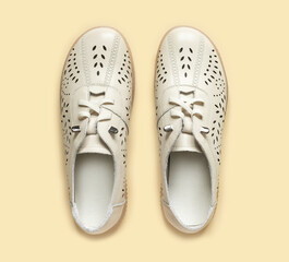 Pale white female shoes on yellow backdrop. Flat lay, top view trendy fashion feminine background.