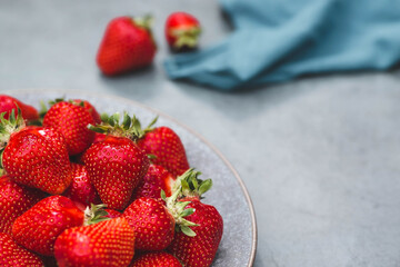 Delicious, fresh strawberries in a stylish plate on a concrete background. Top view with space to copy.
