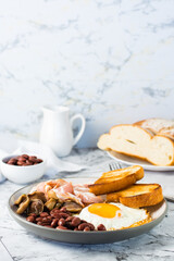 Traditional English breakfast with egg, bacon, beans, mushrooms and toast on a plate. Vertical view