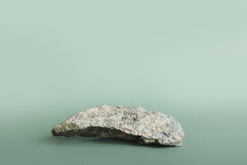 Natural gray stone stand for presentation and exhibitions on pastel green background. Abstract podium for organic cosmetic products. Minimal style. Selective focus