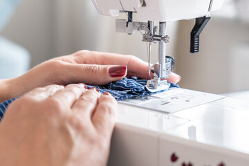 woman hands close up sewing on machine stitching fabric material