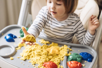 Cute little boy playing with kinetic sand. Development of fine motor skills. Early sensory...