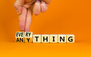 Anything or everything symbol. Businessman turns cubes, changes the concept word Anything to Everything. Beautiful orange background. Business motivational anything or everything concept. Copy space.