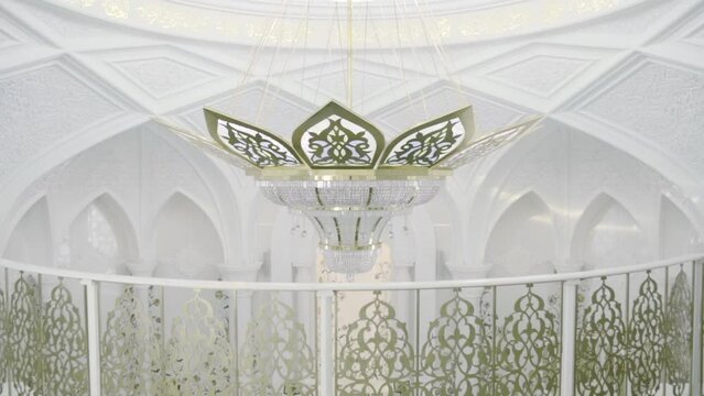 Interior of the mosque with decorative ceiling. Scene. White beautiful mosque with golden carved railings and a dome.