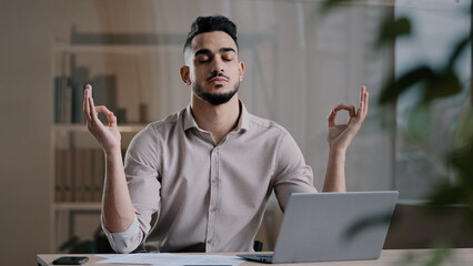 Calm arabian business man professional worker eyes closed taking break meditating on work desk...