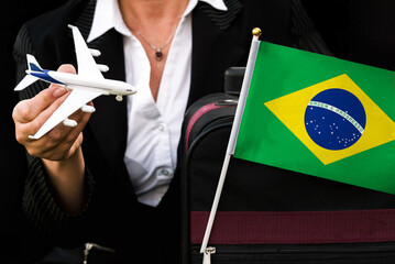  business woman holds toy plane travel bag and flag of Brazil
