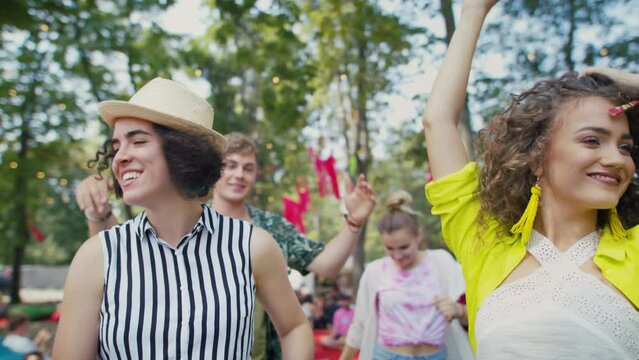 Group of young friends at summer festival, having good time, dancing.