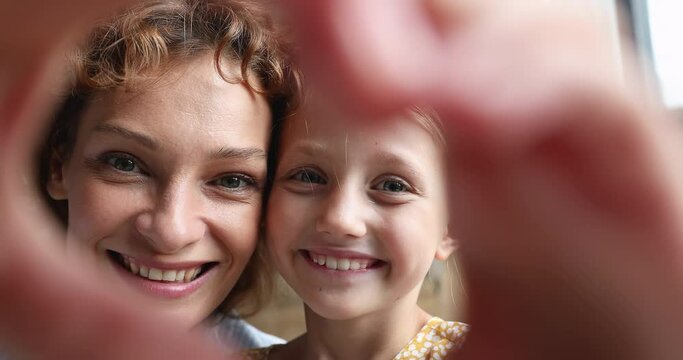 Close up sincere attractive bonding young mother and little preschool kid daughter showing heart symbol to camera, showing love and devotion, feeling happy enjoying tender family lovely relations.