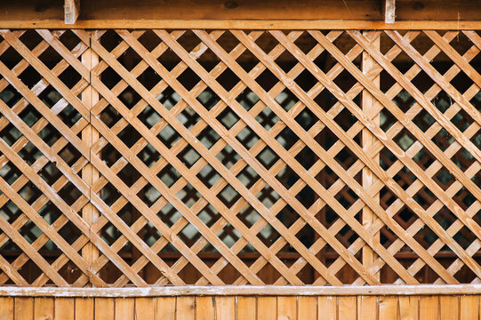 Wooden fence, lattice in rhombuses close-up. Photography, background.