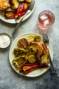 Overhead view of a plate of roasted peppers, garlic and sour cream sauce and pink drinks