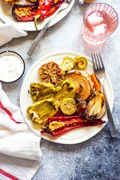 Overhead view of a plate of roasted peppers, garlic and sour cream sauce and pink drinks