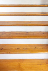 Vintage wooden stair with brown plank tread and white riser. Wood shelf on white painted wall.