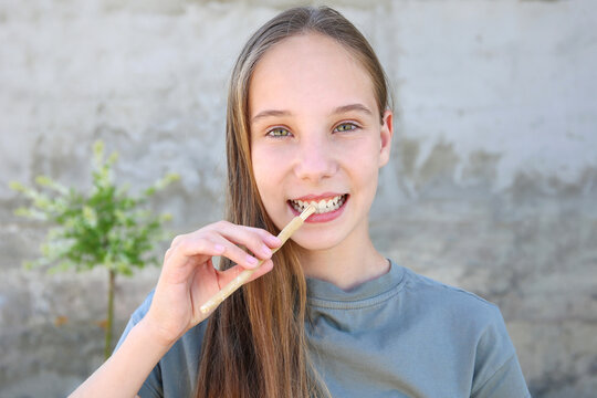A girl brushes her teeth siwak stick. Miswak sticks.