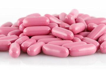 Obraz na płótnie Canvas Pink capsules with medical drugs or supplements isolated on white background, top view.