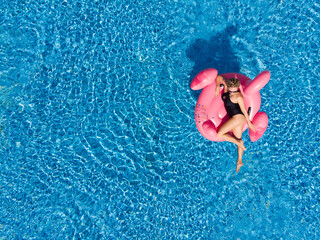 Woman on flamingo pool float in sea, drone aerial view. Summer holidays