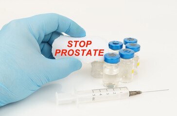 In his hand is a piece of paper with the inscription - STOP PROSTATE, next to it lies a syringe and injection jars.