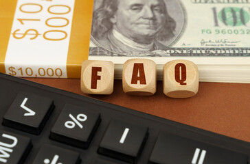 On the table are dollars, a calculator and cubes with the inscription - FAQ