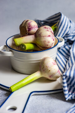 Close-up of raw garlic bulbs in a bowl on a chopping board with a napkin