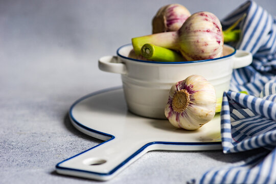 Close-up of raw garlic bulbs in a bowl on a chopping board with a napkin