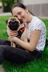 Young girl goes for walk with doggy pug in park. Selective focus.