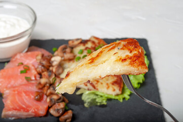 a traditional Swiss dish is strung on a fork - part of a potato pancake. in the background, you can...
