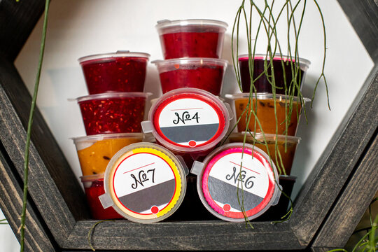 Liquid tea infusion in plastic containers stands on a stand. The concept of healthy eating. Red orange green liquid tea infusion