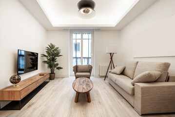 Modern living room with a three-seater sofa, a wooden side table, a wooden sideboard with drawers and a TV above it.