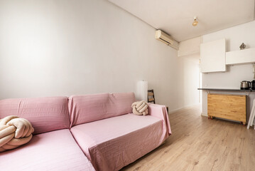 Living room with sofa with pink fabric, chestnut wood floors and light wood dining table