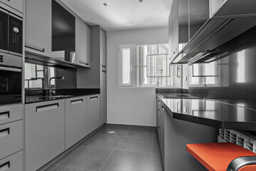 Image of a kitchen with gray wood cabinets to match the flooring, black stone countertops, and black built-in appliances