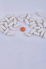 Pile of white medical pills and one colorful pill on white background. Space for text.