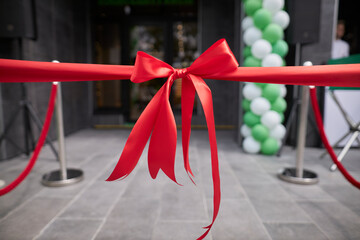 Red ribbon bow at the store opening. Event. - obrazy, fototapety, plakaty